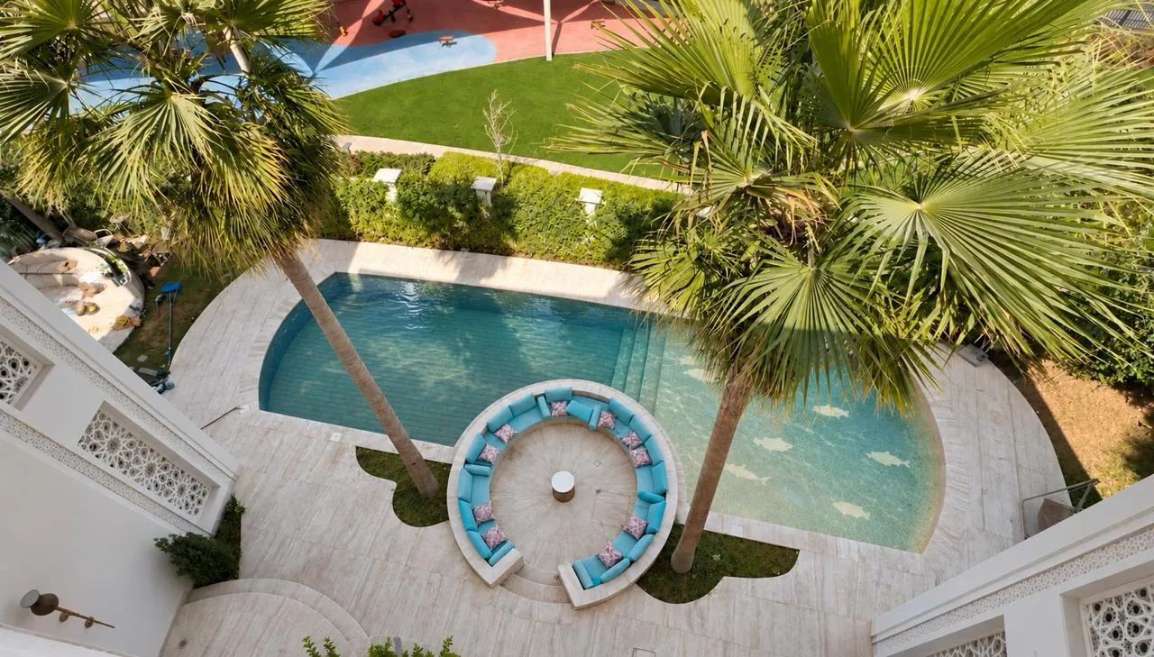 Aerial view of a Dubai residence pool with a WaveLift movable floor, framed by palms and a sunken seating area